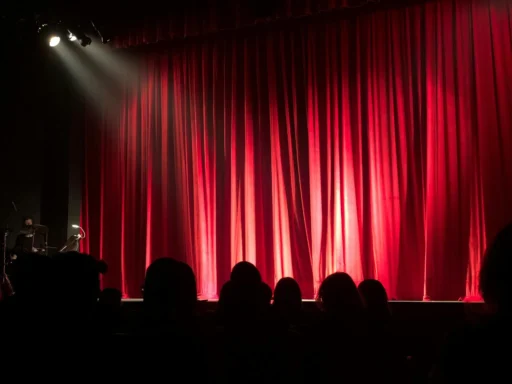 En standup komedi scen med röd garding i bakgrunden. Bästa standup komiker just nu