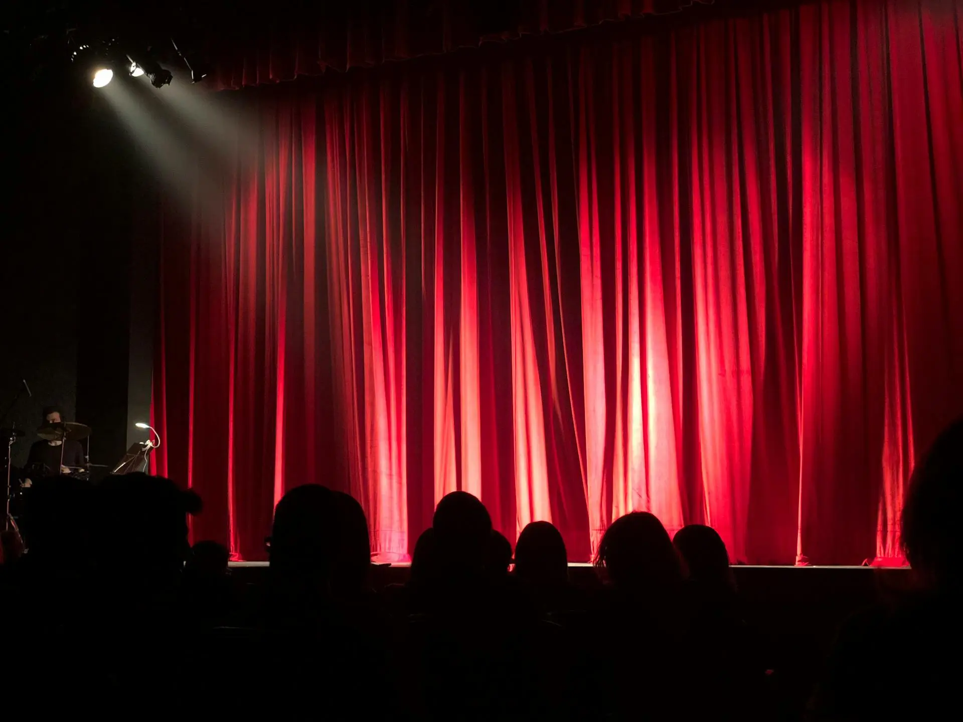 En standup komedi scen med röd garding i bakgrunden. Bästa standup komiker just nu