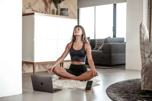 Kvinna mediterar i sitt vardagsrum med app på mobilen