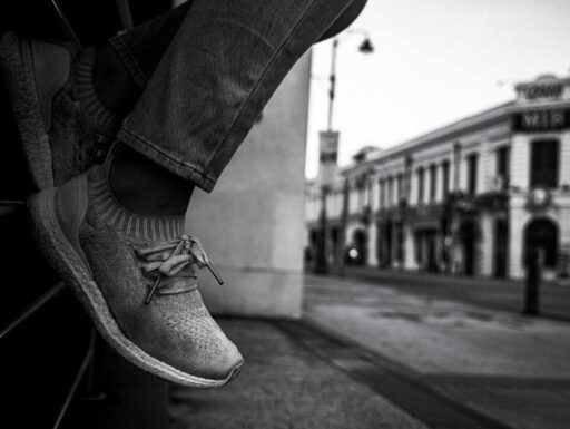 Person sitter på staket, svart vit bild. ARtikeln handlar om designern Johan Lindeberg