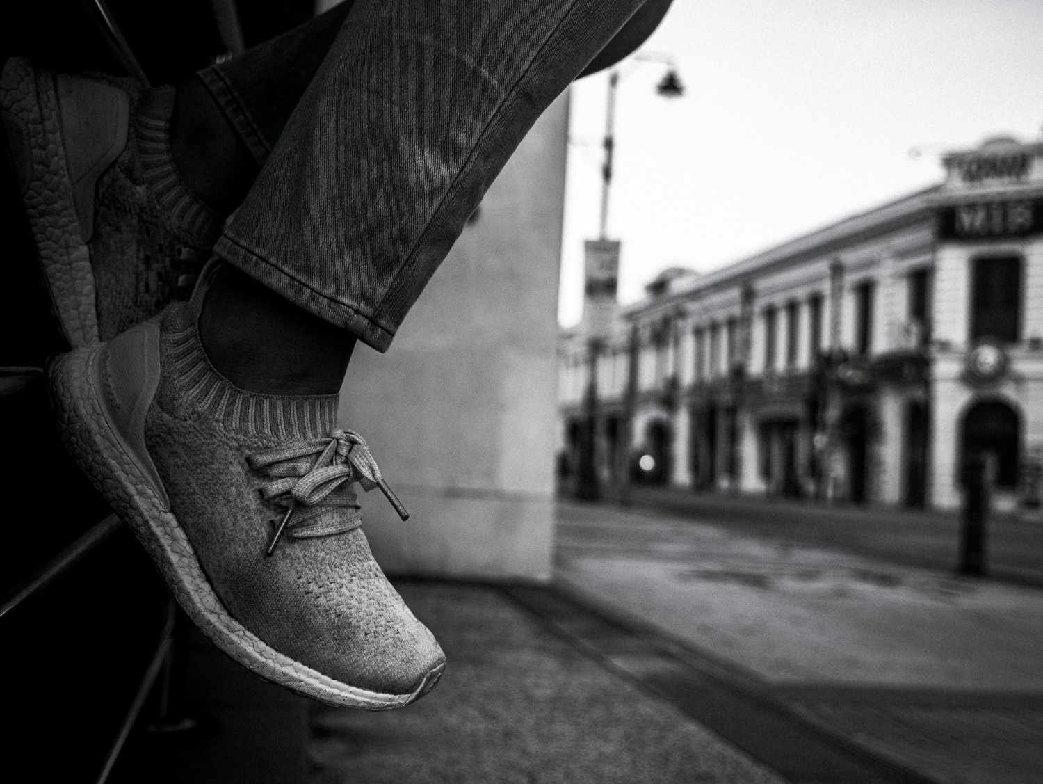 Person sitter på staket, svart vit bild. ARtikeln handlar om designern Johan Lindeberg